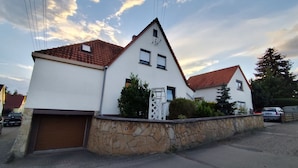 Une maison à deux étages, avec des fondations en pierre, un toit recouvert de tuiles rouges et un garage.