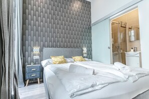 A modern hotel room with a large bed, bedside lamps, a nightstand, and a bathroom visible through an open door. - Beautiful Room, Wifi & TV, Near Mariahilferstraße (Vienna)