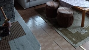 A cozy living room with a grey sofa, two round wooden stools, a coffee table, and a stone fireplace. - Chata Bobík (Oravice)