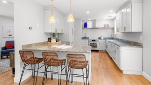 A modern kitchen with white cabinetry, a large island with bar stools, and pendant lighting. - 4-bedroom house in Tisbury for a relaxing getaway - newly renovated (Tisbury)