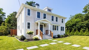 A two-story house with a front porch, a chimney, and a well-maintained lawn. - 4-bedroom house in Tisbury for a relaxing getaway - newly renovated (Tisbury)