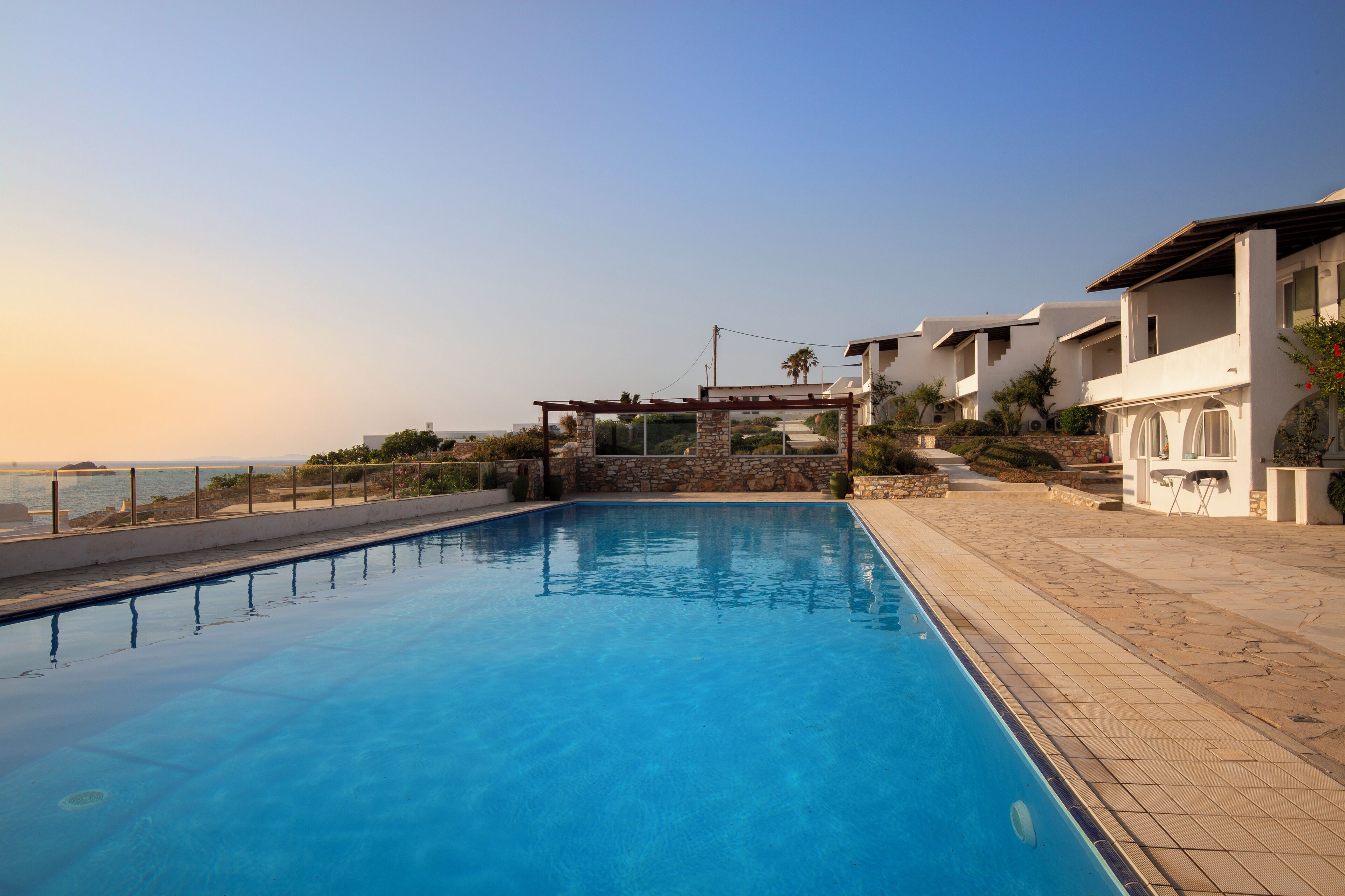 Una piscina con vista despejada al mar, un muro de piedra y una estructura de pérgola.