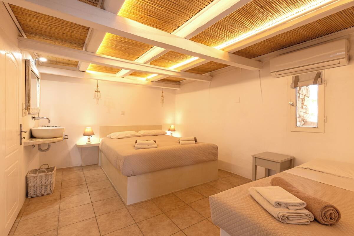 A hotel room with a bed, bedside table, lamp, and a small table with a basket.