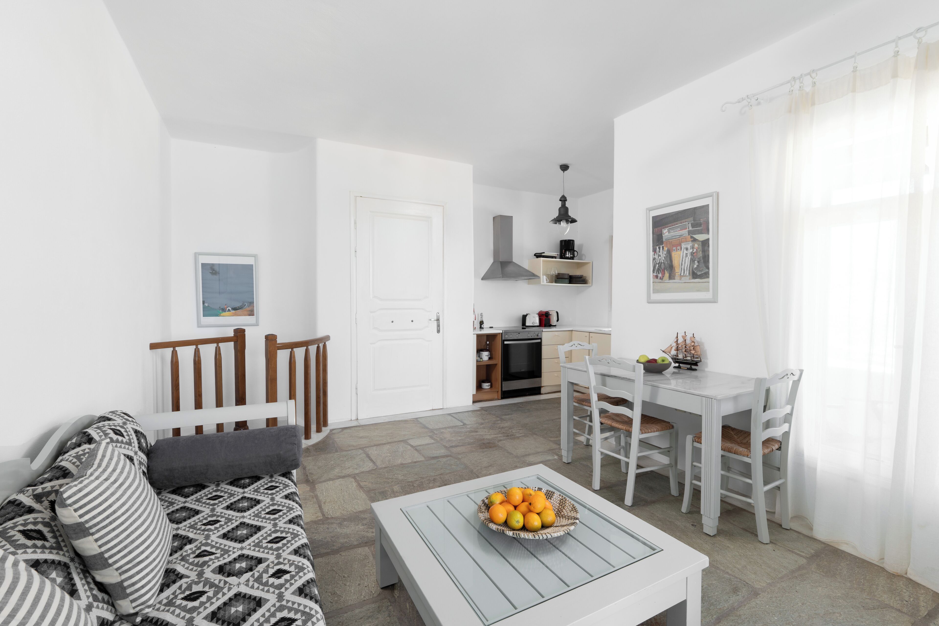 Ein modernes Wohnzimmer mit einer Couch, einem Esstisch mit Stühlen und einer Küchenzeile im Hintergrund.