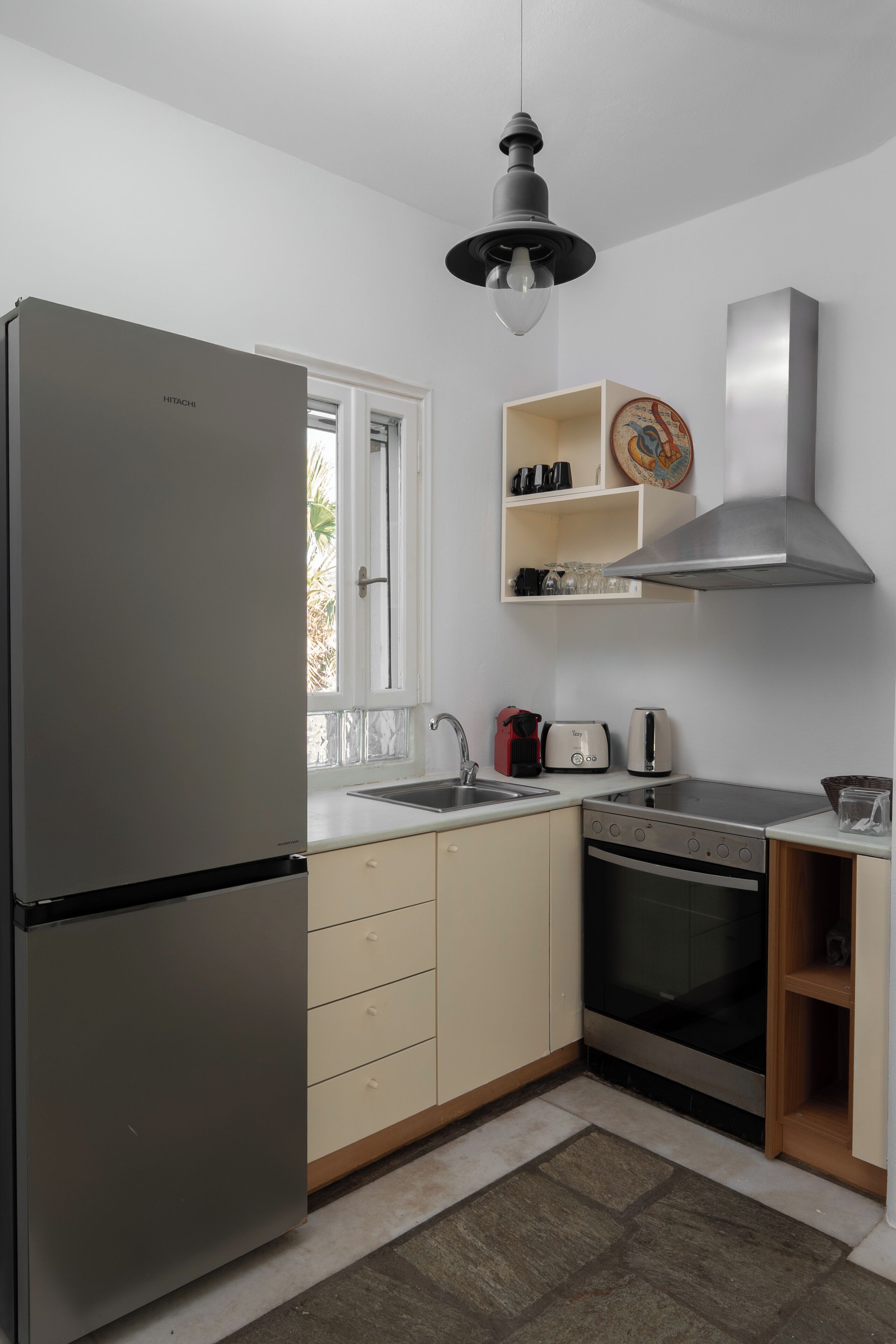 Una cocina moderna con un refrigerador de acero inoxidable, un tostador, un hervidor y una estufa.