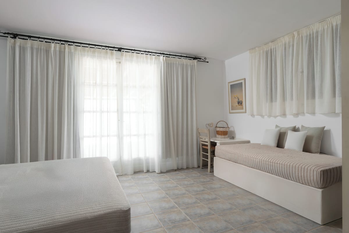 A minimalist room with a bed, a small table, and a chair.