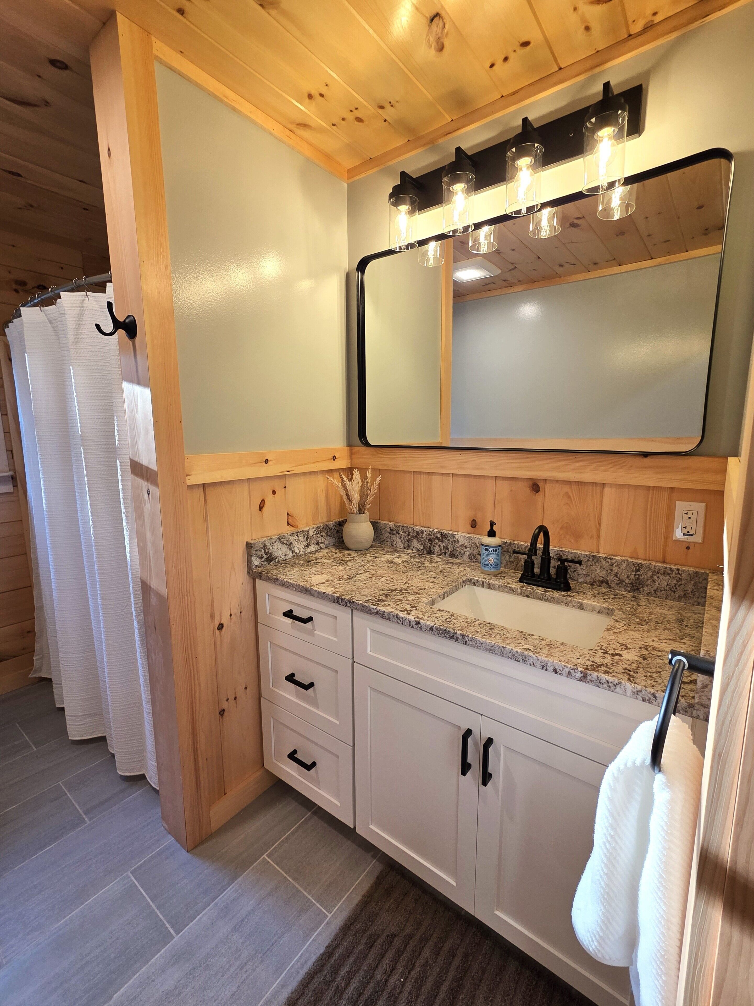 A bathroom with a granite countertop, a sink, a mirror, and a towel rack.