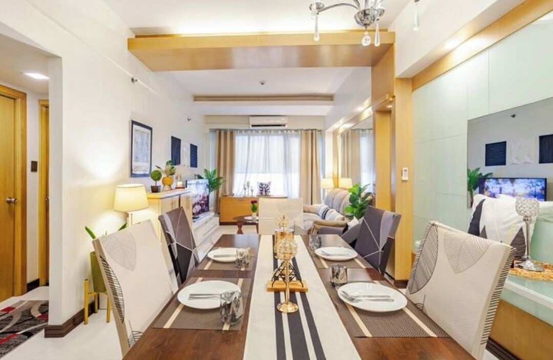 A modern dining area with a long table set for six, surrounded by upholstered chairs.