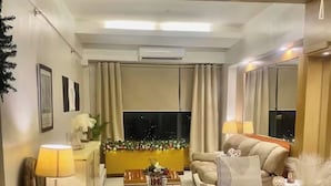 A modern living room with a sofa, coffee table, and dining area. - Stunning Suite 10 Steps from Eastwood Mall (Quezon City)