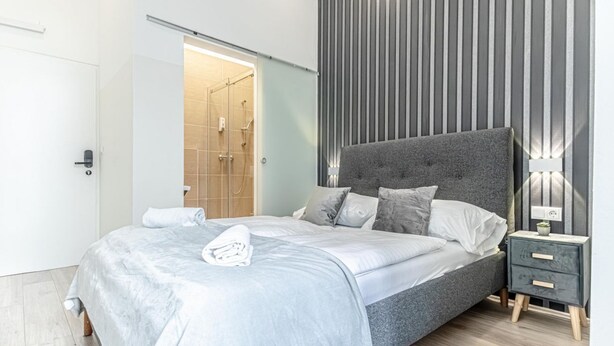 Un dormitorio moderno con una cama grande, una mesita de noche y una zona de ducha.