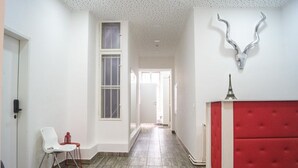 Un pasillo con un banco tapizado rojo, una silla blanca y una cornamenta decorativa en la pared.
