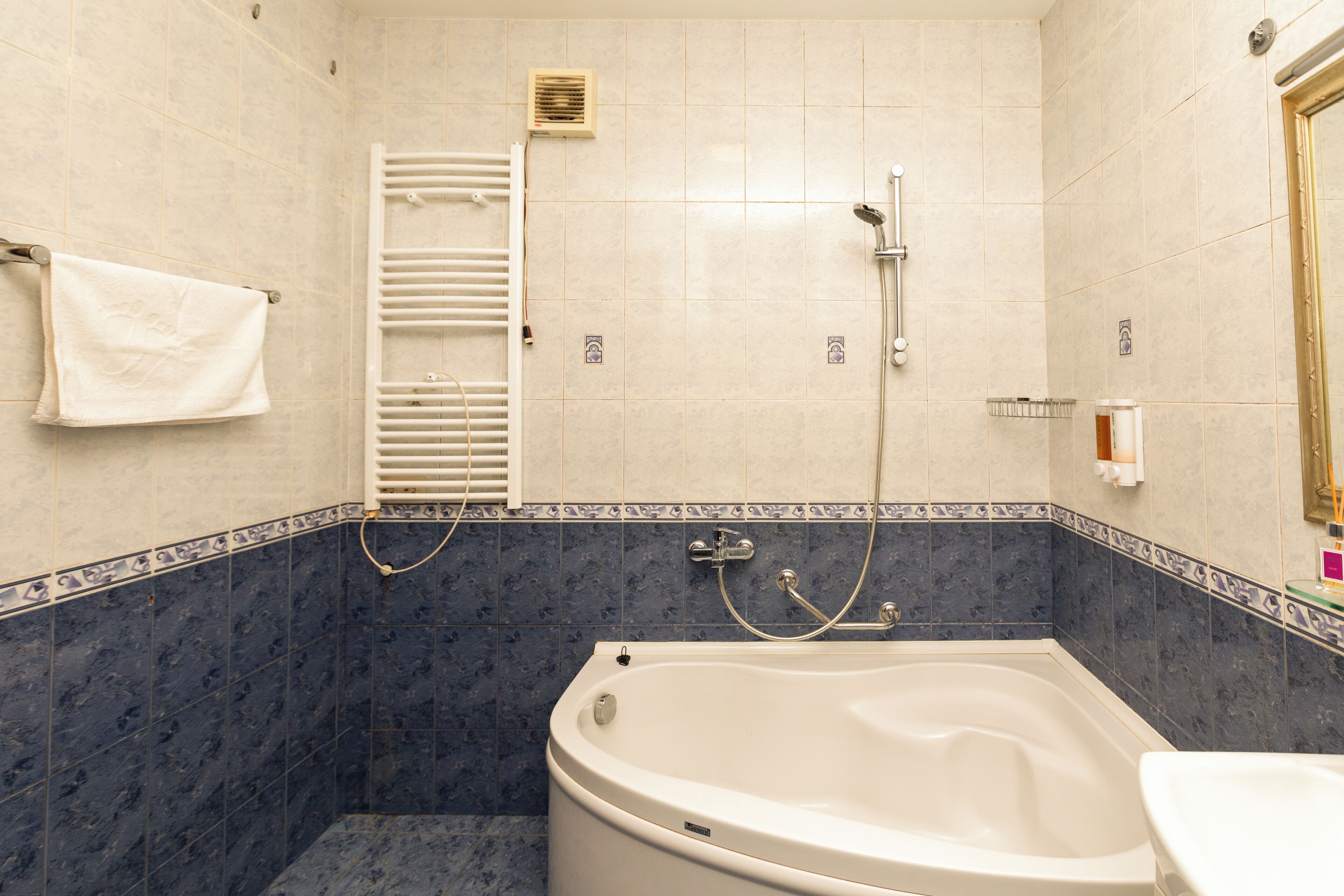 A bathroom with a bathtub, a towel rack, and a shower area.