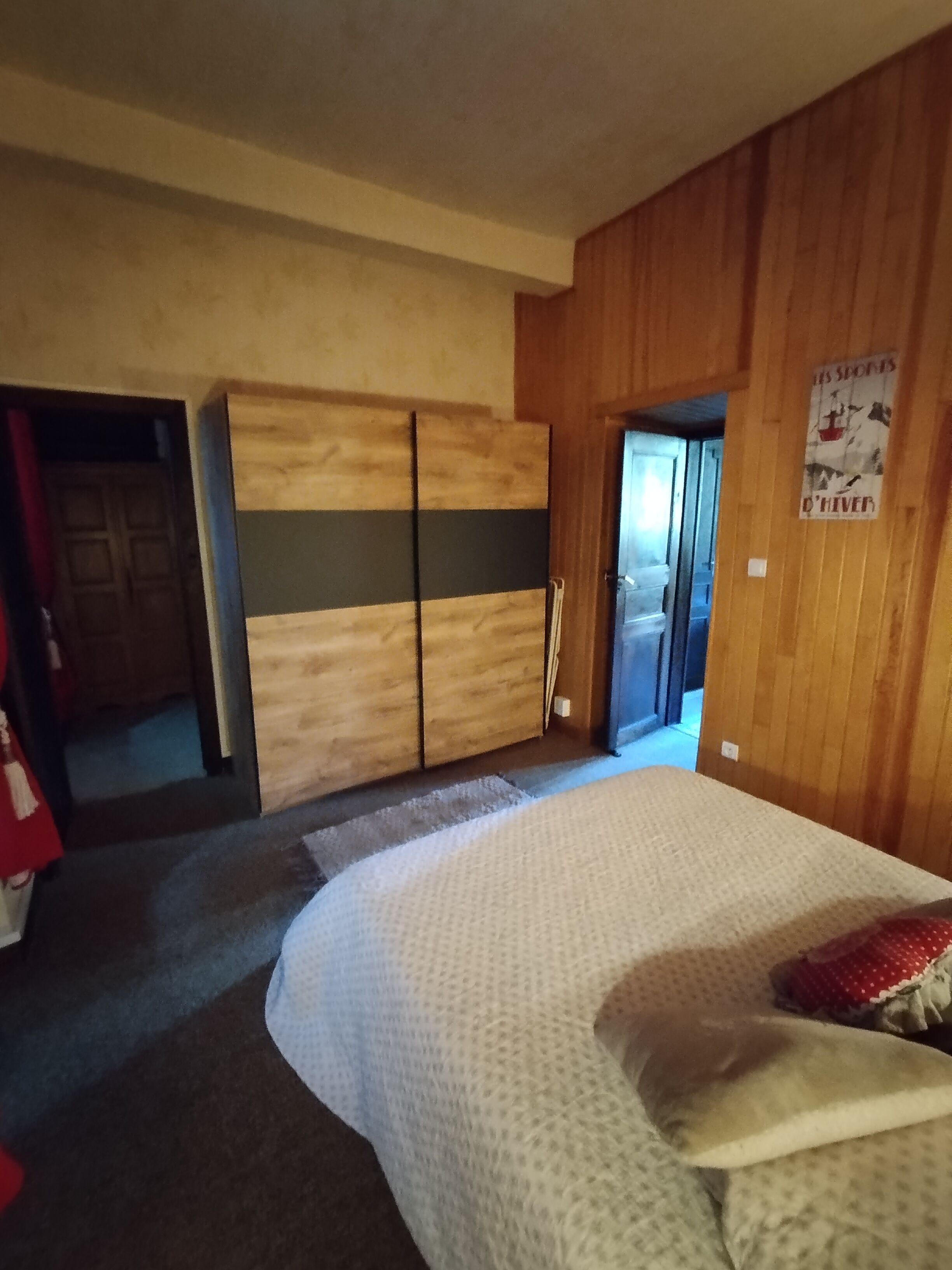 Une chambre à coucher avec un lit, une armoire en bois et une affiche accrochée au mur.