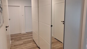Un couloir doté d’un plancher en bois, de murs blancs et d’une armoire à miroir avec une porte coulissante.