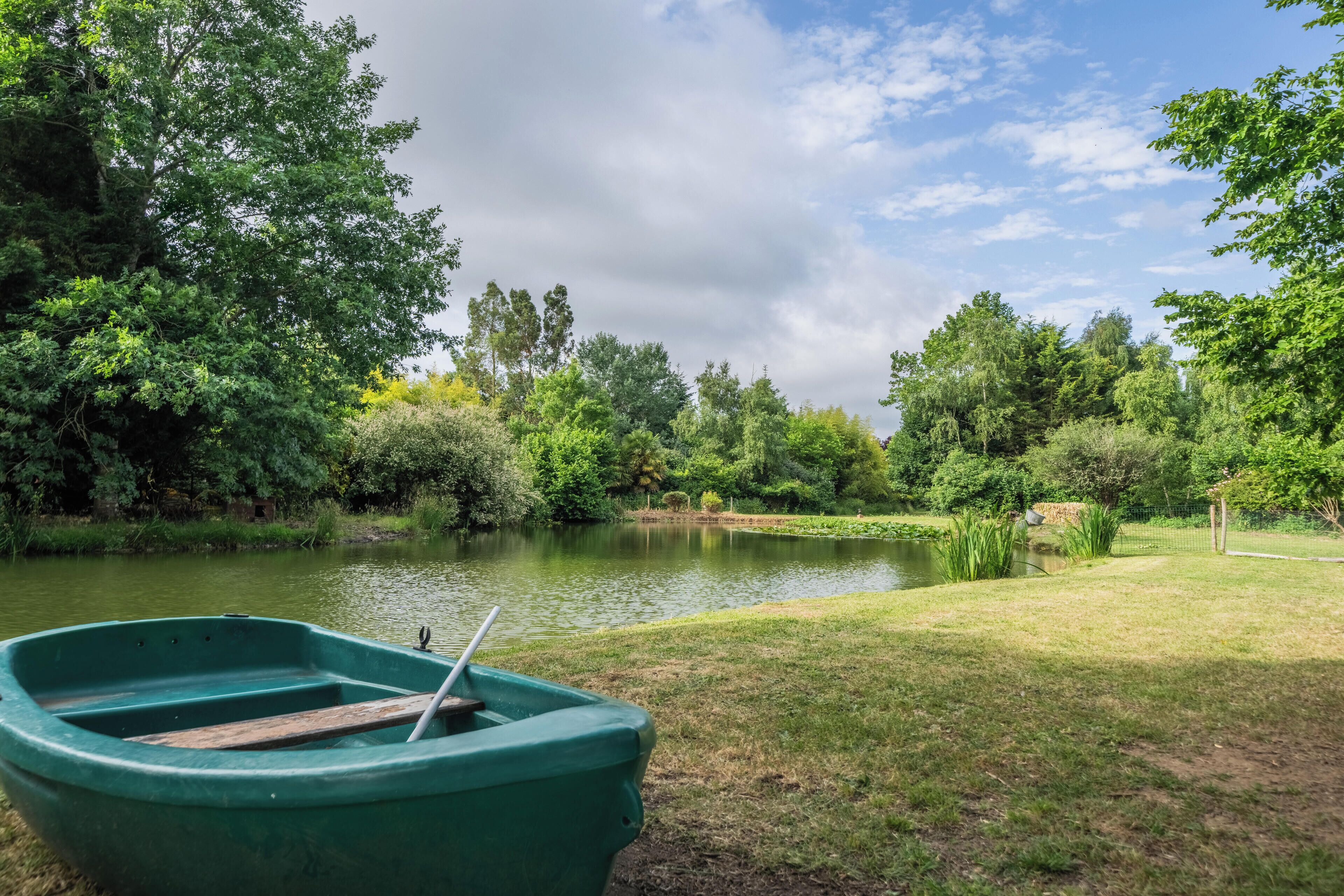 A green boat on a calm lake surrounded by lush greenery and trees.