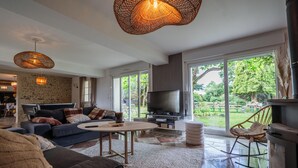 Una sala de estar moderna con un sofá, televisor y lámparas de mimbre.