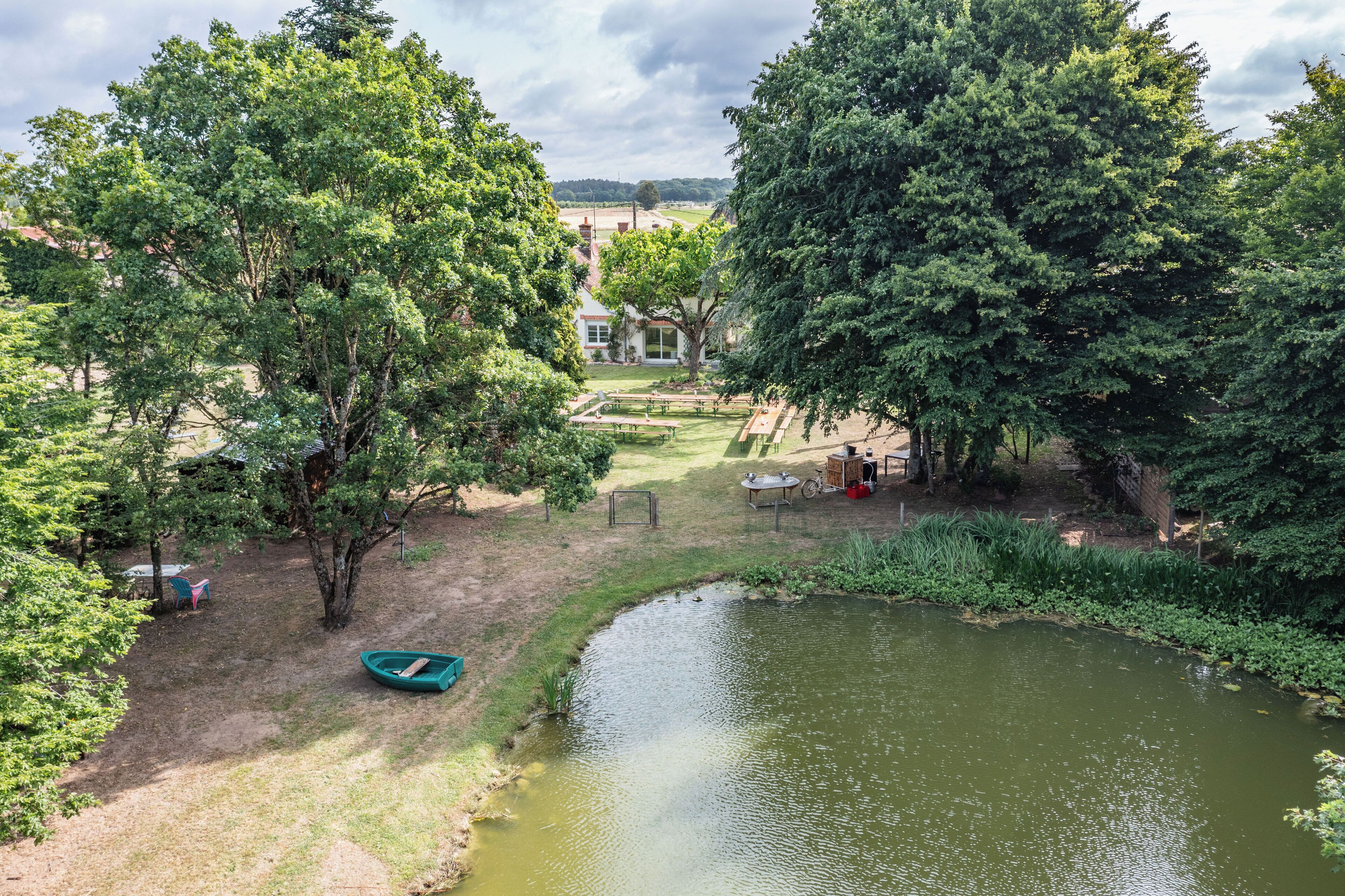 A park with a pond, picnic tables, and a boat.