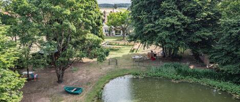 A park with a pond, picnic tables, and a boat.
