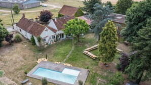 Vista aérea de una zona residencial con piscina, casas y abundante vegetación.