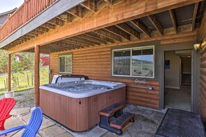 A wooden cabin with a hot tub, outdoor seating, and a view of the landscape. - Deluxe Granby Ranch Hillside Home: Private Hot Tub (Granby)
