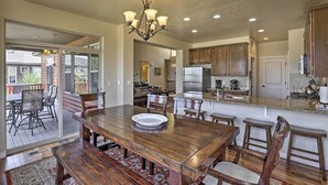 A spacious kitchen with wooden cabinets, a large island, and a dining area with a wooden table and chairs. - Deluxe Granby Ranch Hillside Home: Private Hot Tub (Granby)