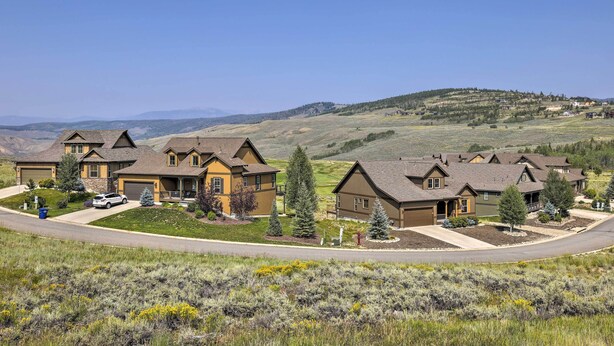 A residential area with houses featuring a mix of brown and yellow exteriors, surrounded by green lawns and trees. - Deluxe Granby Ranch Hillside Home: Private Hot Tub (Granby)