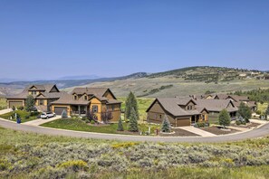 A residential area with houses featuring a mix of brown and yellow exteriors, surrounded by green lawns and trees. - Deluxe Granby Ranch Hillside Home: Private Hot Tub (Granby)
