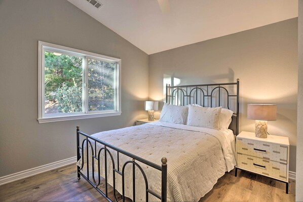 A bedroom with a bed, nightstands, a window, and a ceiling fan.