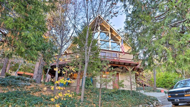 A cabin with a wooden deck, a covered porch, and a flag.