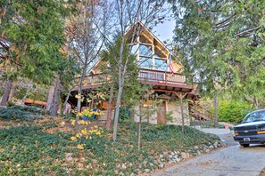 A cabin with a wooden deck, a covered porch, and a flag.
