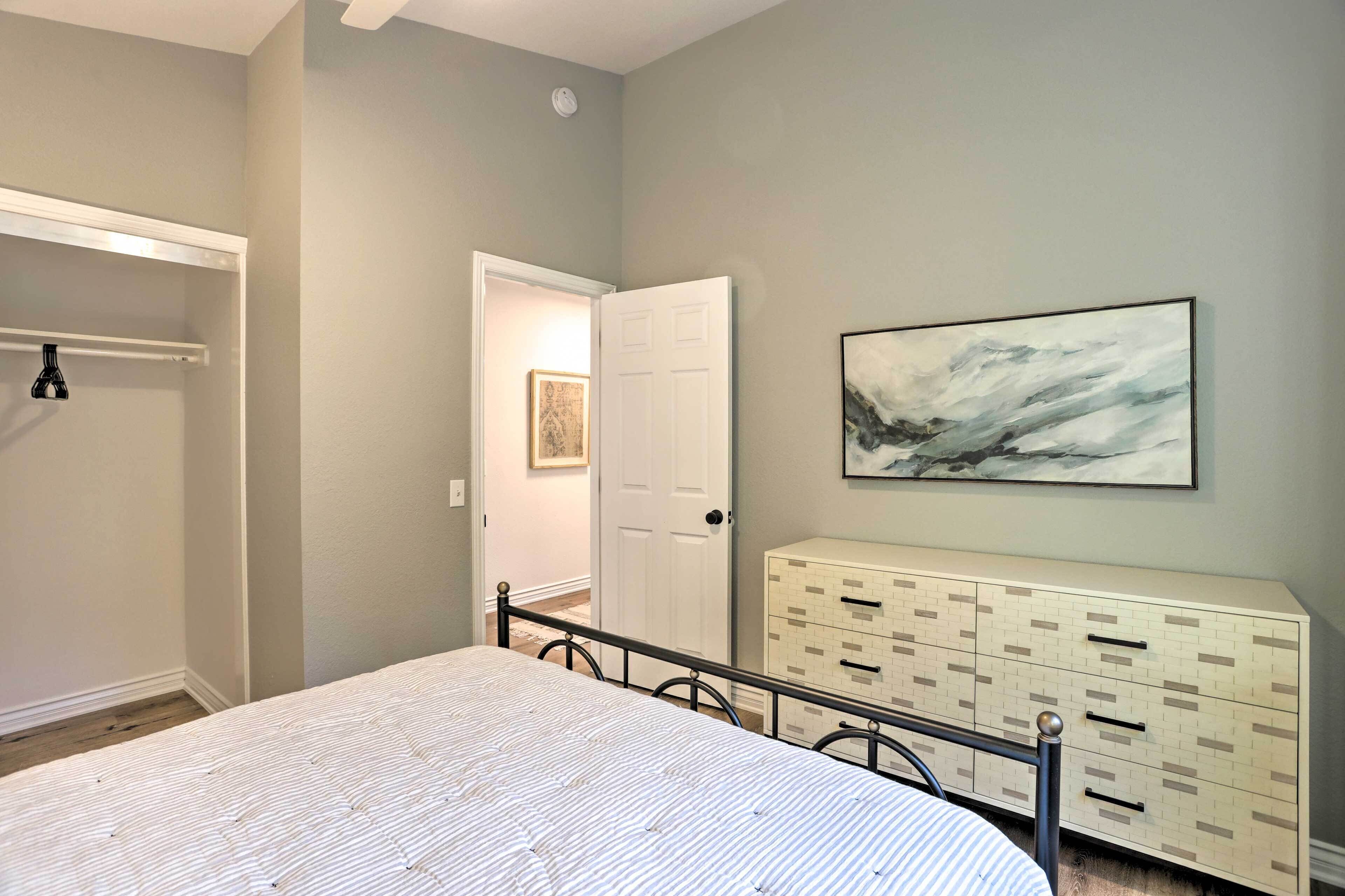Un dormitorio con cama, cómoda y puerta que da a otra habitación.
