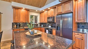 A modern kitchen with wooden cabinets, granite countertops, stainless steel appliances, and a large island with seating.