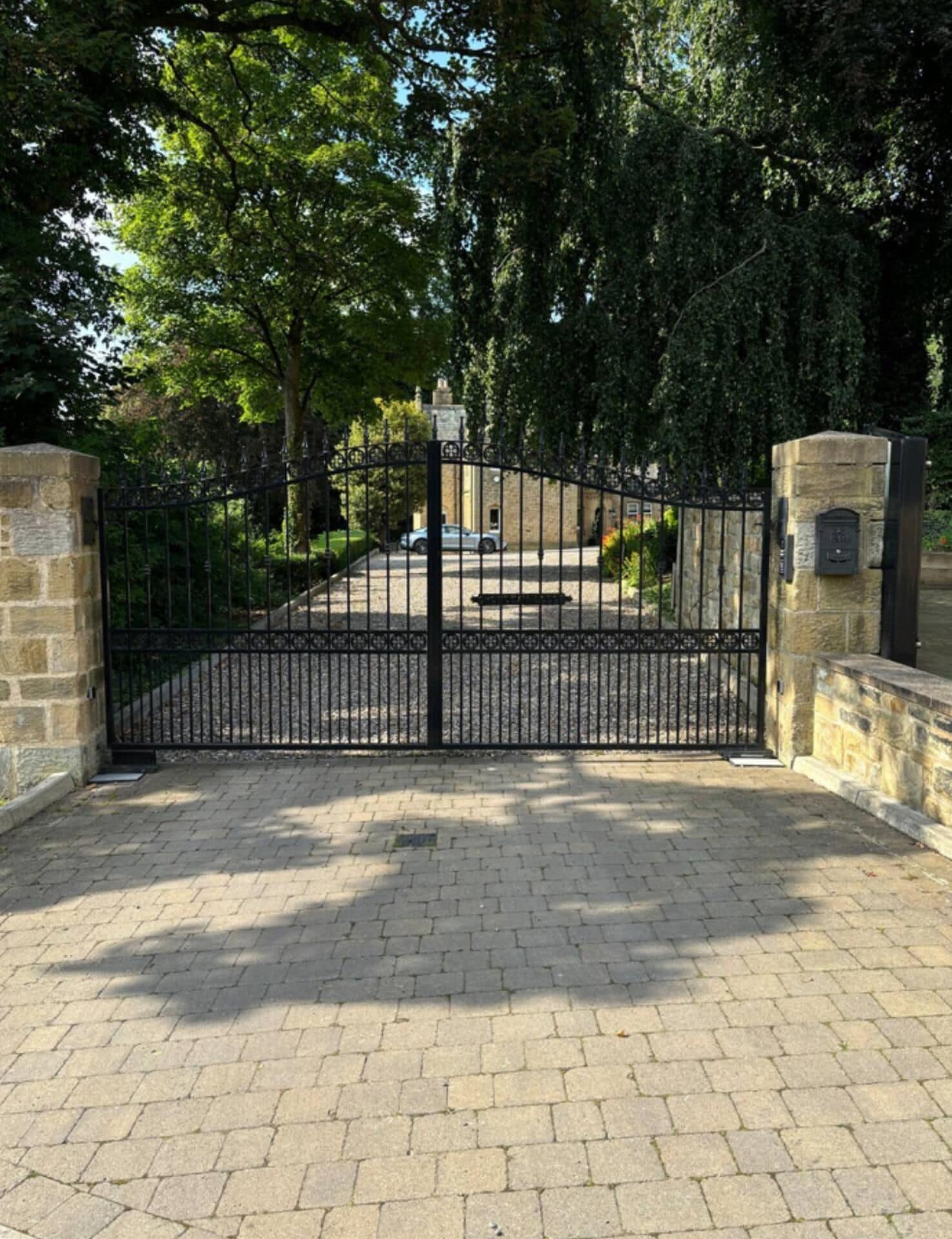 A gated entrance with a paved driveway leading to a building.