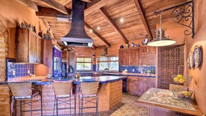 A rustic kitchen with a large island, bar stools, and a tiled backsplash.