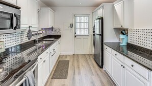 A kitchen with white cabinets, a black refrigerator, a microwave, and a granite countertop. - Easy Intl Soccer Stay < 3 Mi to Hard Rock Stadium (Miami Gardens)