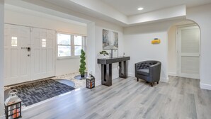 A spacious living room with a grey herringbone floor, a dark grey sofa, a small table with a plant, and a large painting on the wall. - Easy Intl Soccer Stay < 3 Mi to Hard Rock Stadium (Miami Gardens)