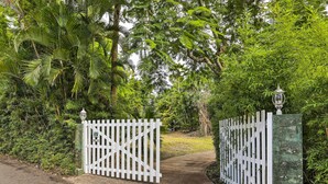 A gated entrance with a white picket fence and a lantern post, surrounded by lush greenery. - Bright St Thomas Getaway W/pool, 3Mi to Magens Bay (St. Thomas)