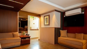 A modern living room with two sofas, a wooden cabinet, a framed picture, and an air conditioning unit. - Hotel Maitreya Inn  (Vellore)