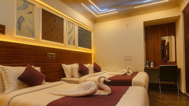 A hotel room with two beds, a desk, and a mirror. - Hotel Maitreya Inn  (Vellore)