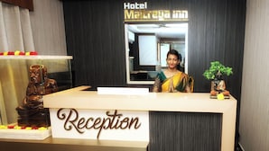 A reception desk with a sign that reads "Reception" and a statue of a seated figure. - Hotel Maitreya Inn  (Vellore)