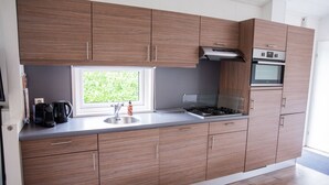 A modern kitchen with wooden cabinets, a built-in stove, and a window providing natural light.