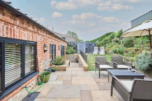 A patio area with outdoor furniture, a brick wall, and a garden. - Host & Stay | Rupert's Barn (Gimingham)