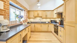 A modern kitchen with wooden cabinets, a built-in oven, and a coffee maker.