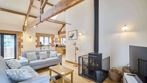 A cozy living room with a sofa, coffee table, fireplace, and a kitchen area in the background.