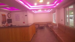 Una zona de recepción con mostrador de madera, asientos y un reloj en la pared.