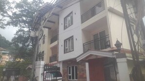 Un edificio de varios pisos con balcones, una entrada protegida por una reja y una señalización visible de un hotel.