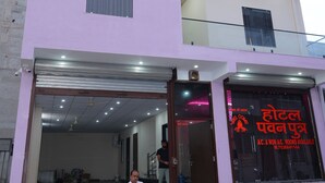 A multi-story hotel with a pink facade, a balcony on the upper floor, and a sign indicating rooms are available.