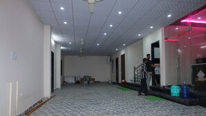 A hallway with tiled flooring, ceiling fans, and a staircase leading to an upper level.