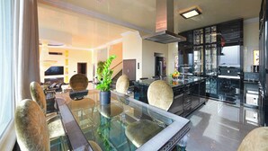 A modern kitchen with black cabinets, a glass island, and a dining area with a glass table and chairs. - Villa Solara – Redefining Luxury Stays in Cyprus (Pegeia, Paphos, Cyprus)
