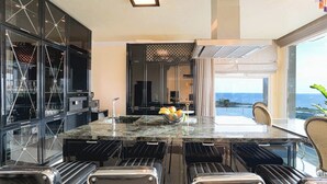 A modern kitchen with a large island, black bar stools, and a view of the ocean. - Villa Solara – Redefining Luxury Stays in Cyprus (Pegeia, Paphos, Cyprus)